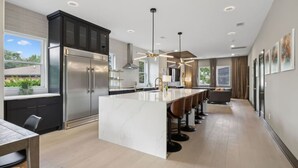 A modern kitchen with a central island, stainless steel appliances, and a dining area with bar stools. - Stunning 4 Bedroom/ 4.5 Bath Home w/Rooftop Deck! (Nashville)