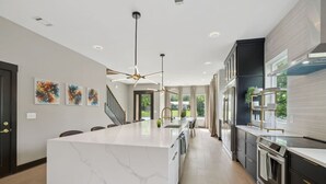 A modern kitchen with a large island, dark cabinetry, and a view to the outdoors. - Stunning 4 Bedroom/ 4.5 Bath Home w/Rooftop Deck! (Nashville)
