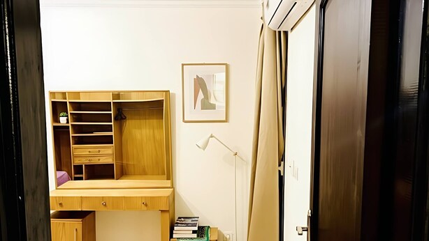 Une pièce comprenant un bureau en bois, un tableau abstrait encadré, un lampadaire et une armoire.