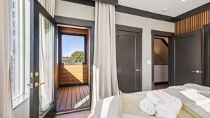 A bedroom with a large bed, a balcony, and a view of the outdoors.