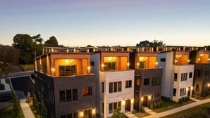 A modern multi-story residential building with a symmetrical facade, large windows, and a central courtyard.