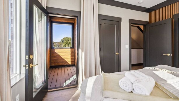 A bedroom with a bed, a window, and a door leading to a balcony. - East Nash Luxury Escape w/Rooftop Deck-Sleeps 12! (Nashville)