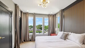 Una habitación de hotel moderna con una cama grande, vistas al exterior y una lámpara de techo contemporánea.