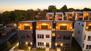 Un moderno complejo residencial con varias edificaciones de dos pisos, destacando amplias ventanas y un patio central.