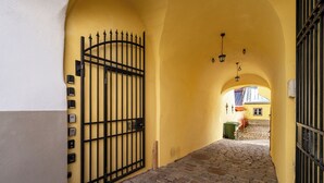 A narrow cobblestone alleyway with a yellow wall and a black metal gate. - Toompea Castle 2-Storey Unique Apartment (Tallinn)