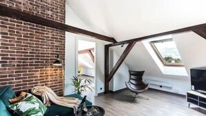 A loft-style room with exposed brick walls, a green sofa, a modern chair, and a skylight. - Toompea Castle 2-Storey Unique Apartment (Tallinn)