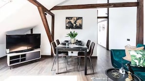 A modern living room with a dining table, chairs, a flat-screen TV, and a green sofa. - Toompea Castle 2-Storey Unique Apartment (Tallinn)