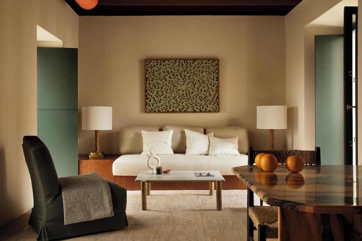 A modern hotel room with a sofa, a coffee table, a dining table, and two lamps.
