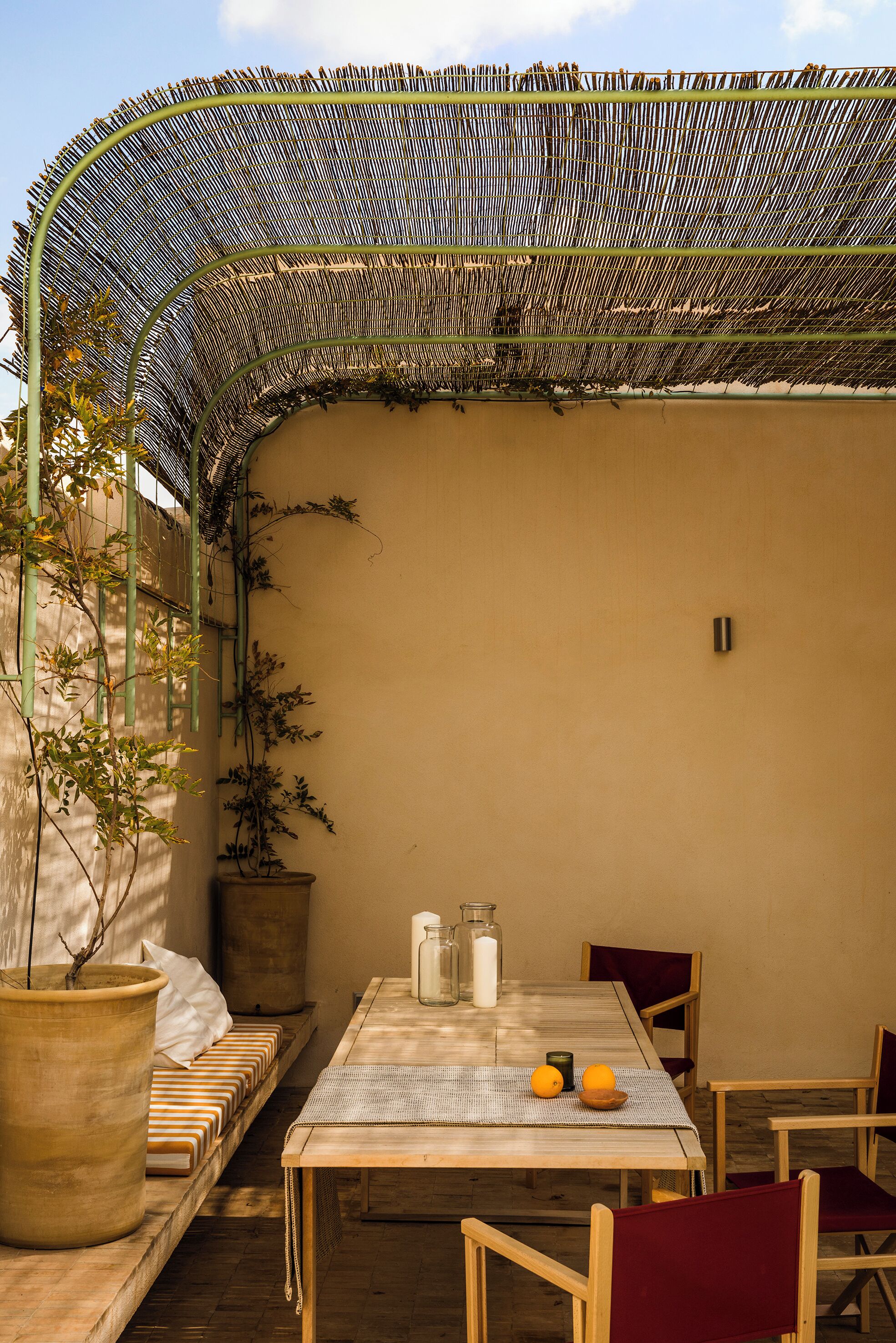 A covered patio with a table, chairs, and potted plants.