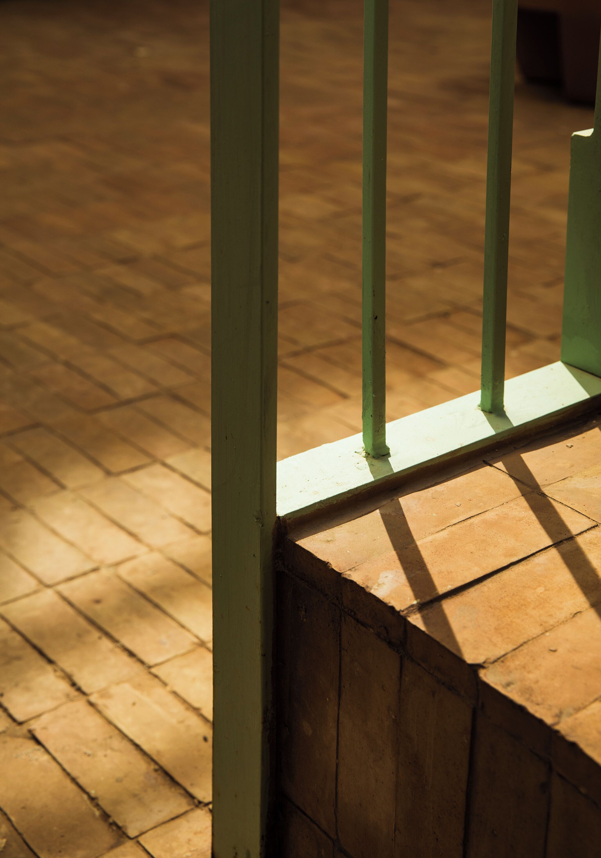 Een houten vloer met een groene metalen balustrade.