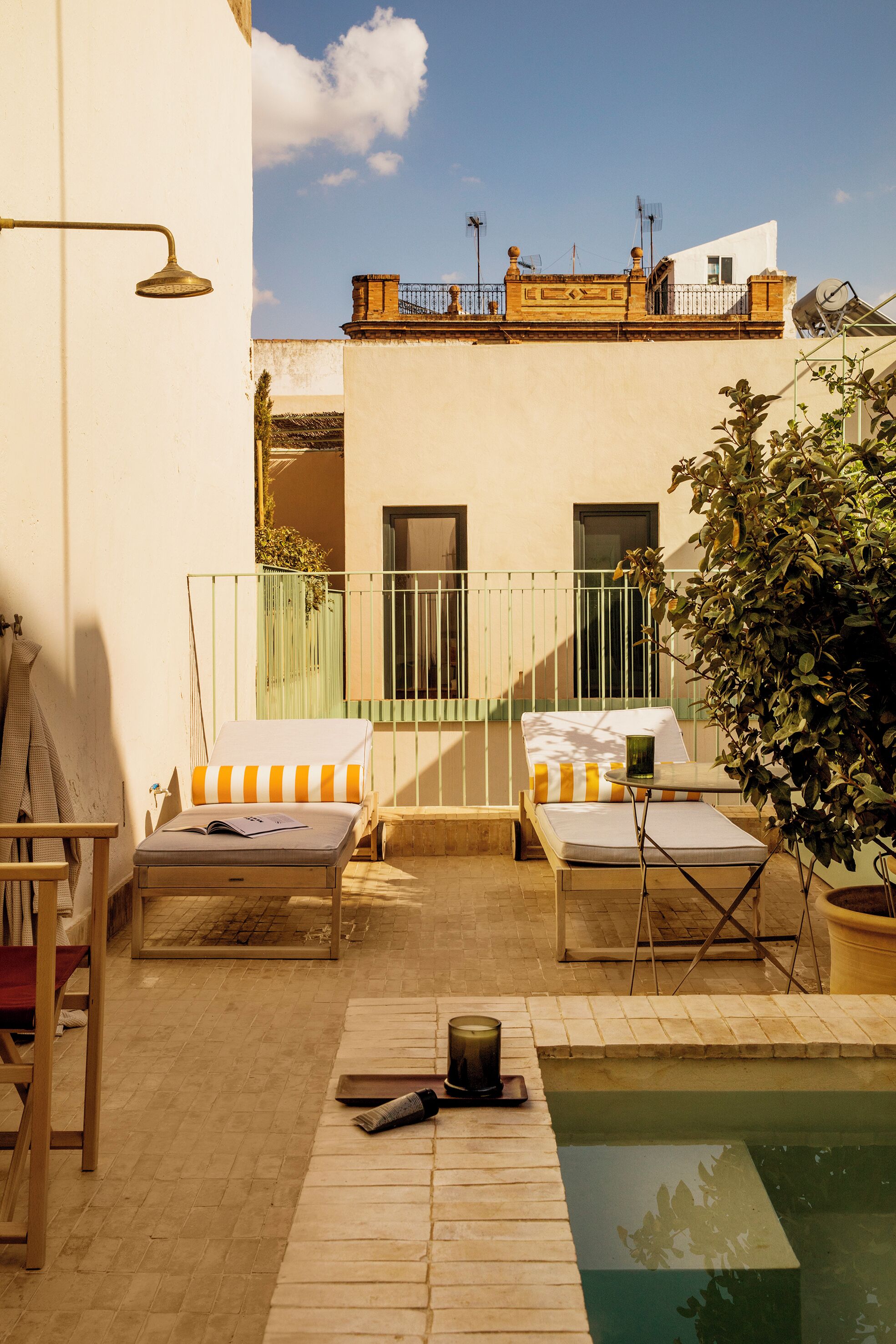 Zona pequeña de piscina al aire libre con sillones de descanso, una mesa y un libro.