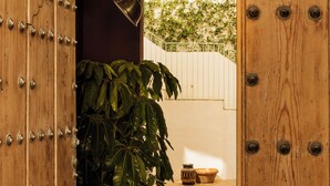 A wooden door with metal studs, a potted plant, and a small table with a bowl. - CSE BOSCOS Apartments (Seville)