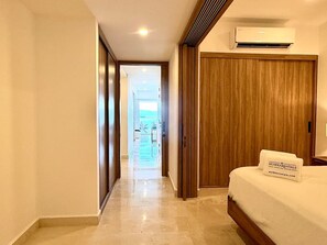 A hotel corridor with a bed, wooden wardrobe, and an air conditioning unit. - Beachfront Harbor171 Condo | Ocean-View Balcony & Rooftop Pool (Puerto Vallarta)