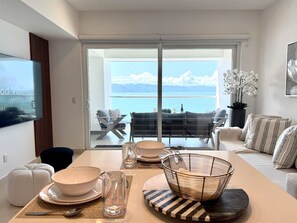 Un comedor moderno con vista al mar, televisor de pantalla plana y un espacio de descanso acogedor.