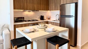 A modern kitchen with wooden cabinets, a stainless steel refrigerator, a gas stove, and pendant lights. - Moikkarentals | Beachfront 1BR Harbor171-N1702 PV (Puerto Vallarta)