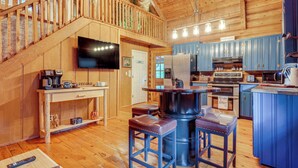 Interno di una baita in legno con angolo cottura, sala da pranzo e una scala.