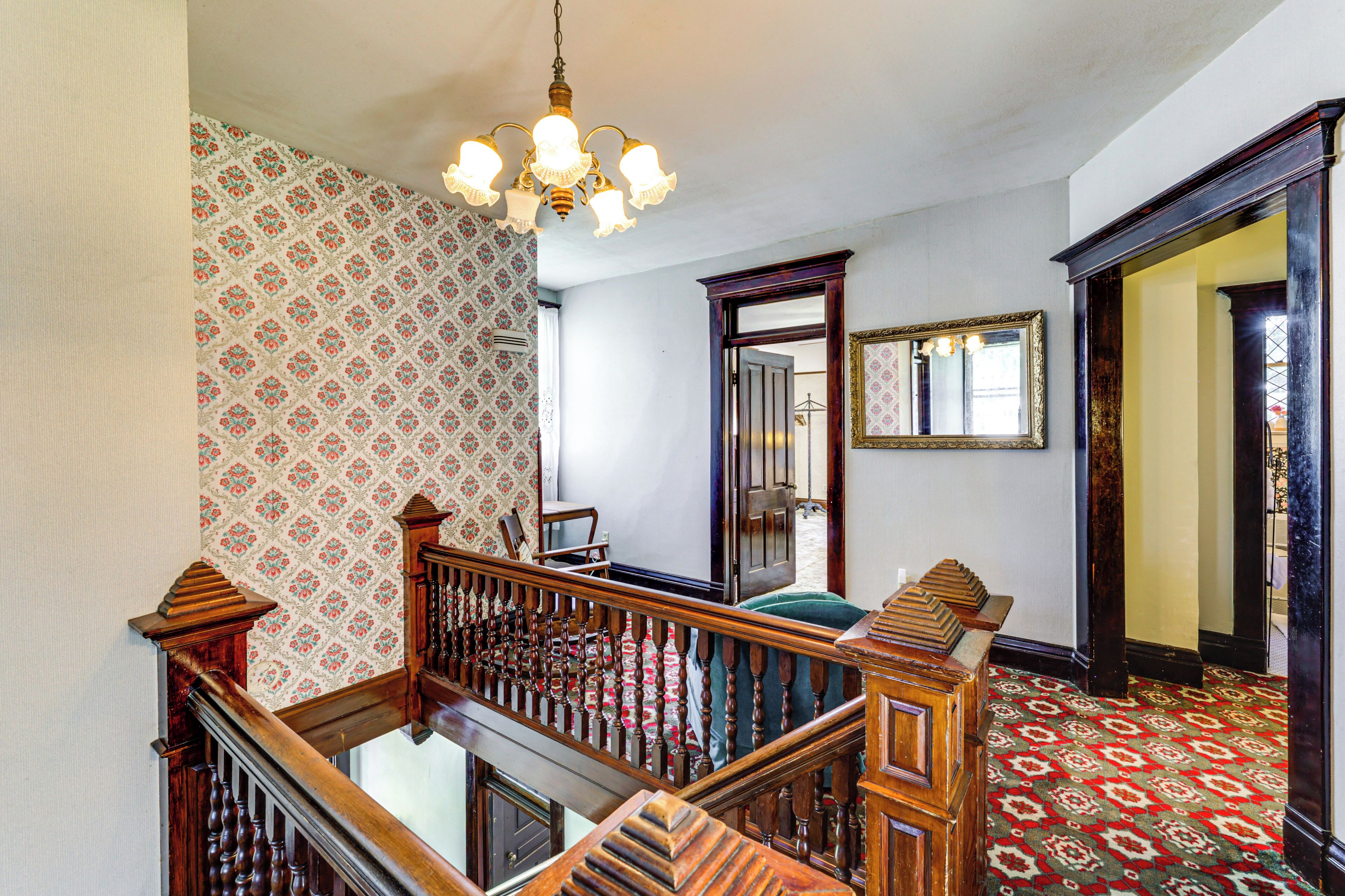 Una escalera con barandilla de madera y alfombra estampada.
