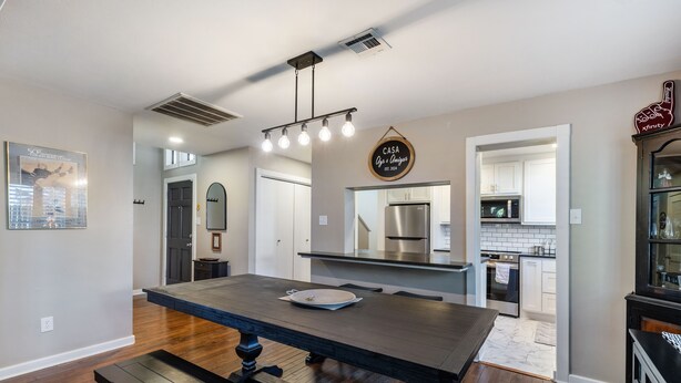 A modern kitchen with a central island, stainless steel appliances, and a dining area with a bench. - 4 mi to Aggieland, Yard & Deck (Bryan)