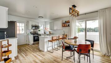 A modern kitchen with white cabinetry, a central island, and a dining area with wooden chairs.