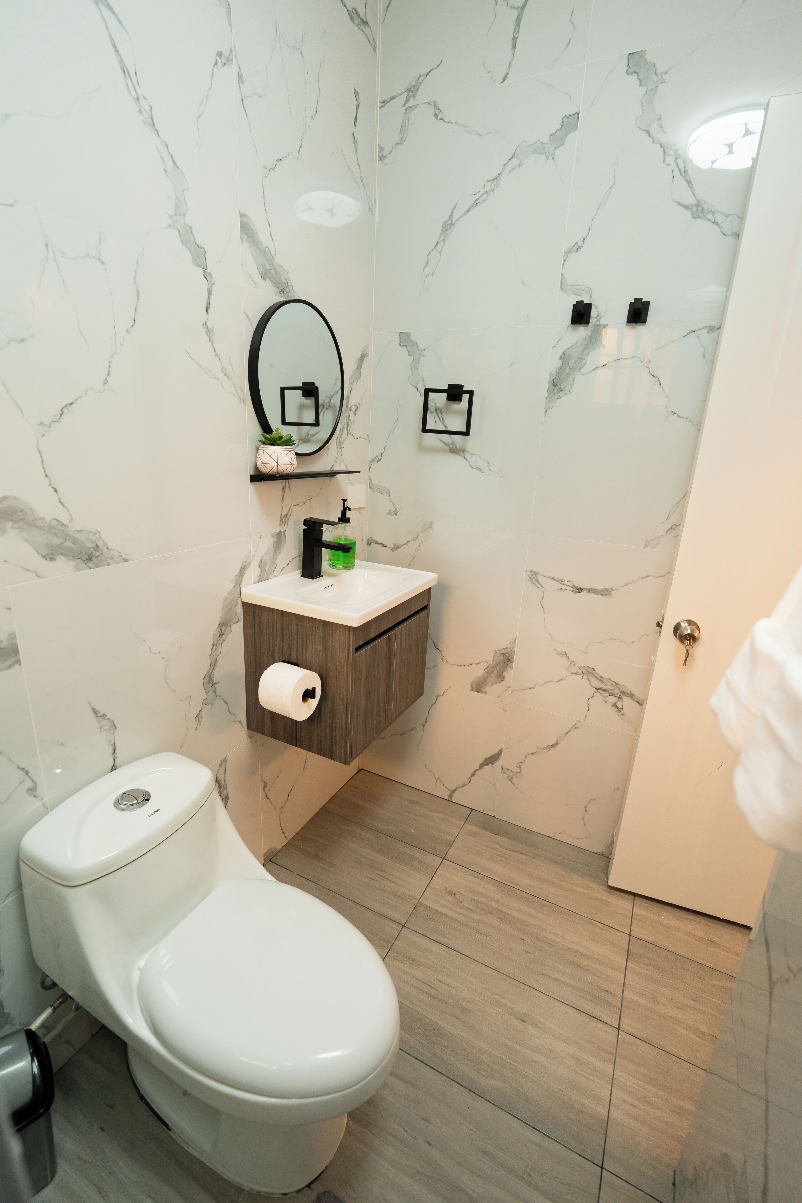 A bathroom with a toilet, a sink with a mirror above it, and a shower area.