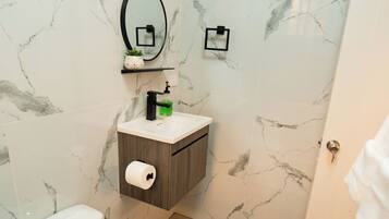 A bathroom with a toilet, a sink with a mirror above it, and a shower area.