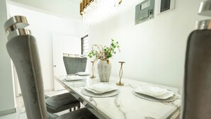 A dining area with a marble table, black chairs, a vase with flowers, and a chandelier.