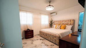 A bedroom with a bed, a dresser, a nightstand, and a ceiling light.