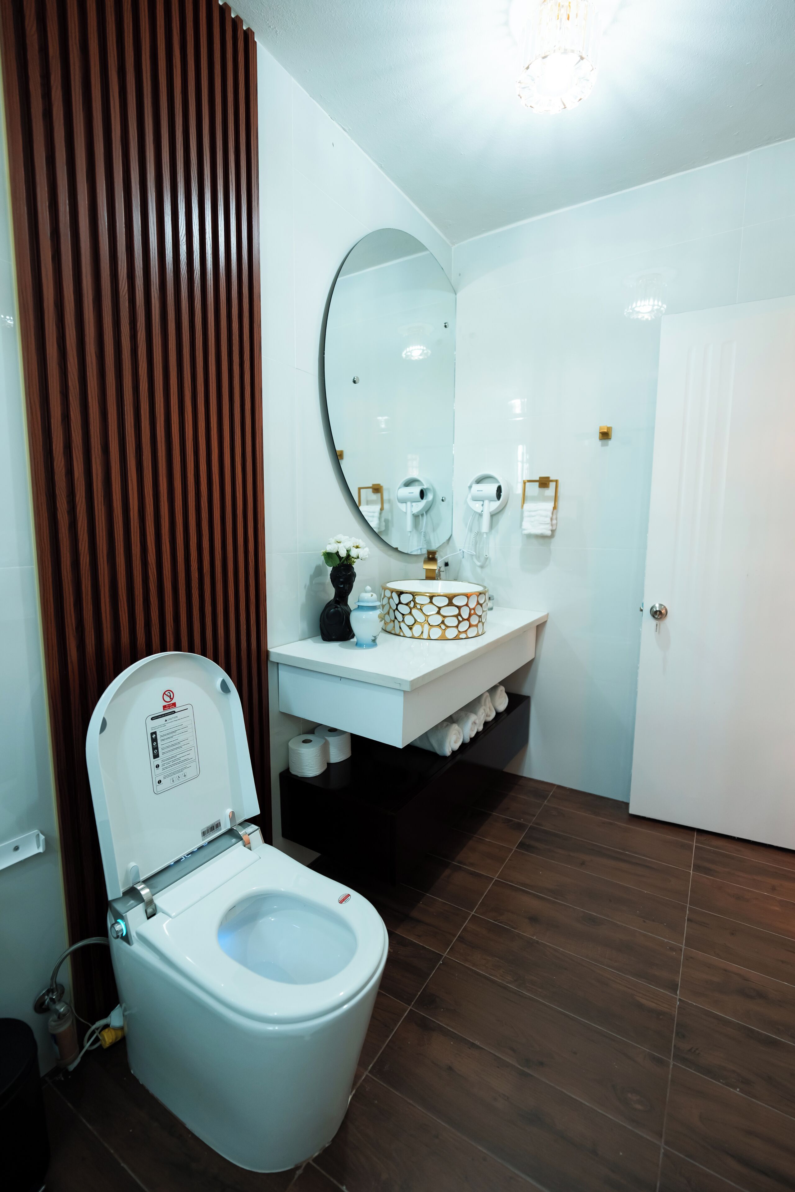 Un baño moderno con inodoro, lavabo, espejo y paneles de madera.