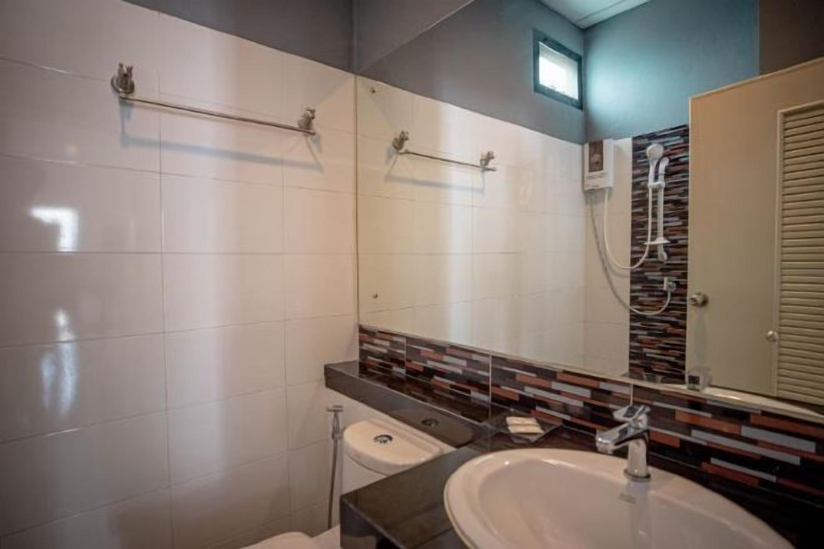 A modern bathroom with a large mirror, a sink, and a shower.