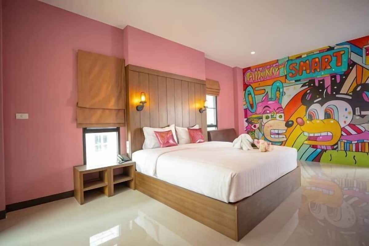 Una camera da letto con un letto, un comodino e un colorato murale sulla parete.