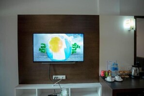 A television mounted on a wall with a wooden panel above it.