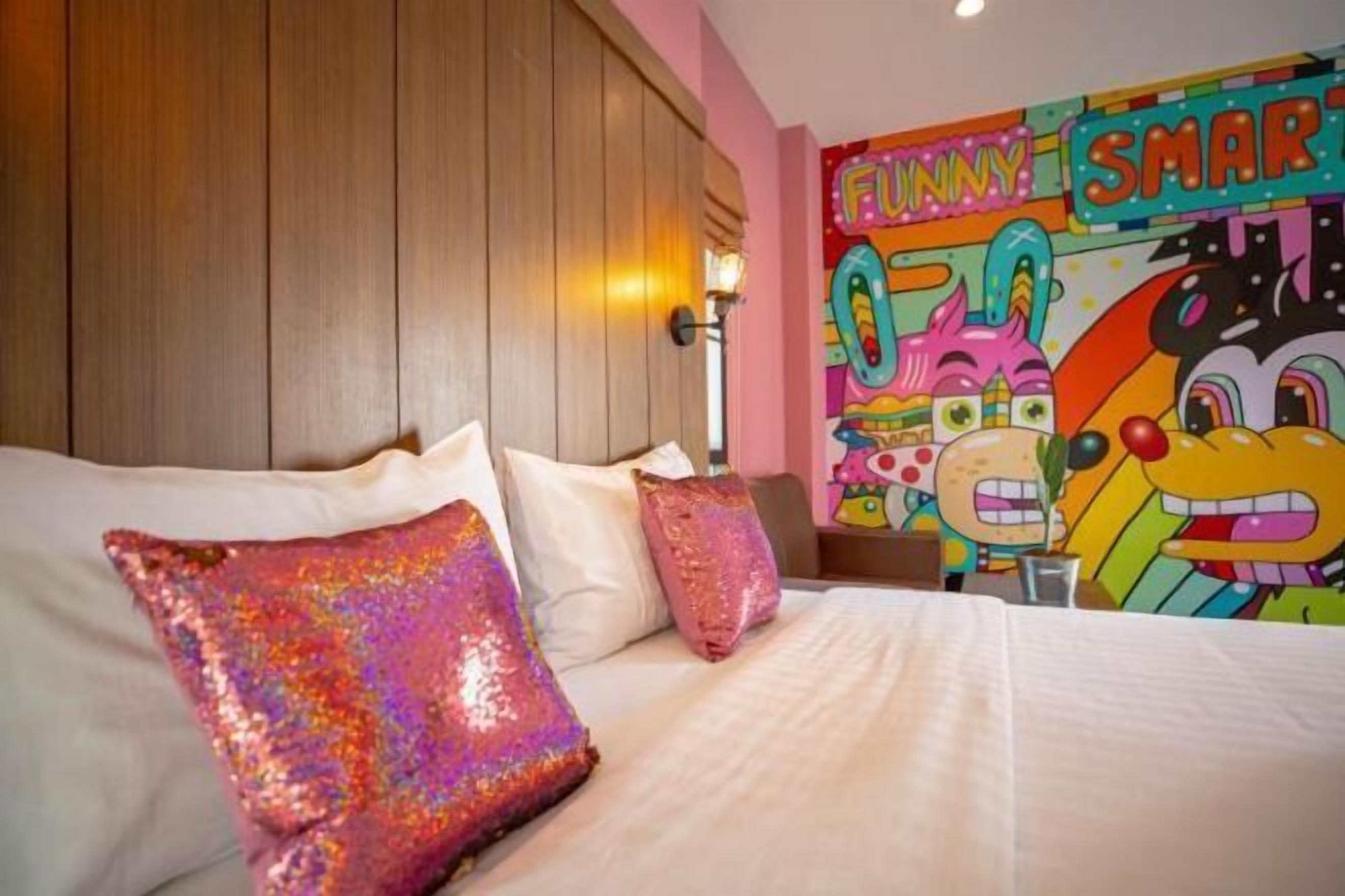 A hotel room with a bed, pillows, and a colorful wall mural.