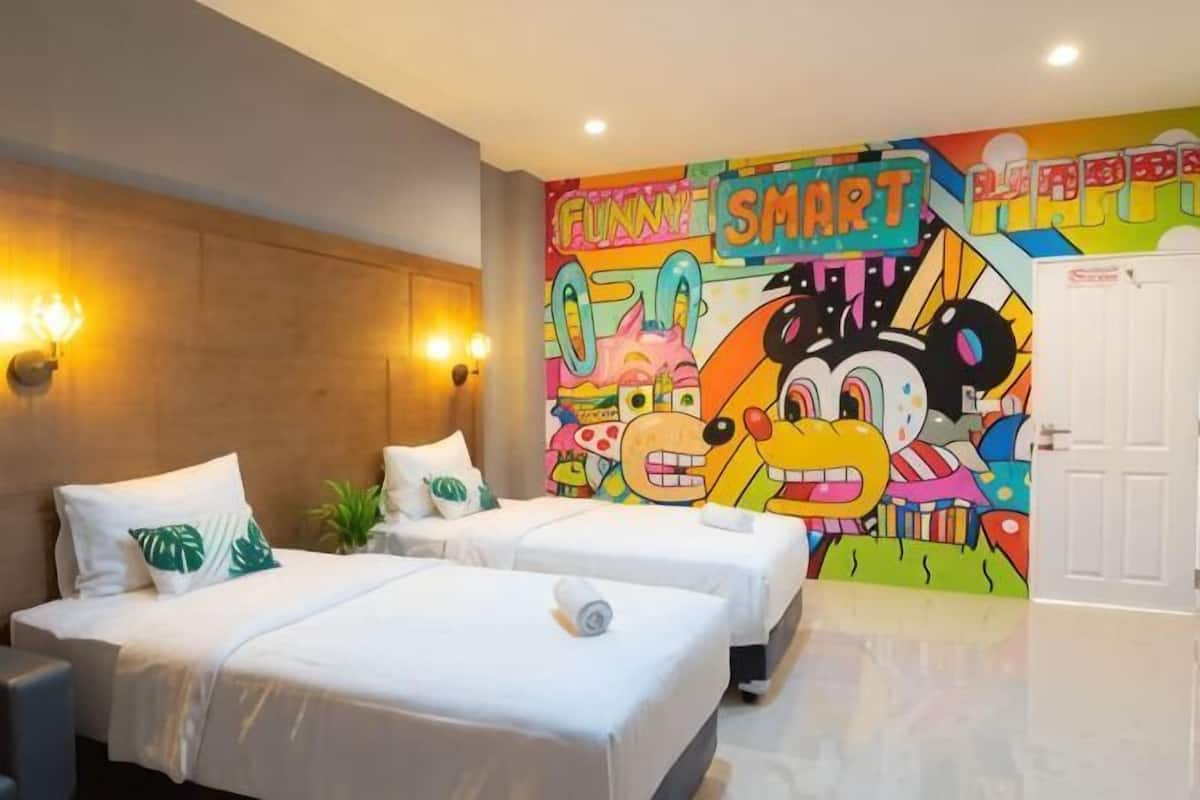 Una camera d'albergo con due letti, un murale colorato e una porta.