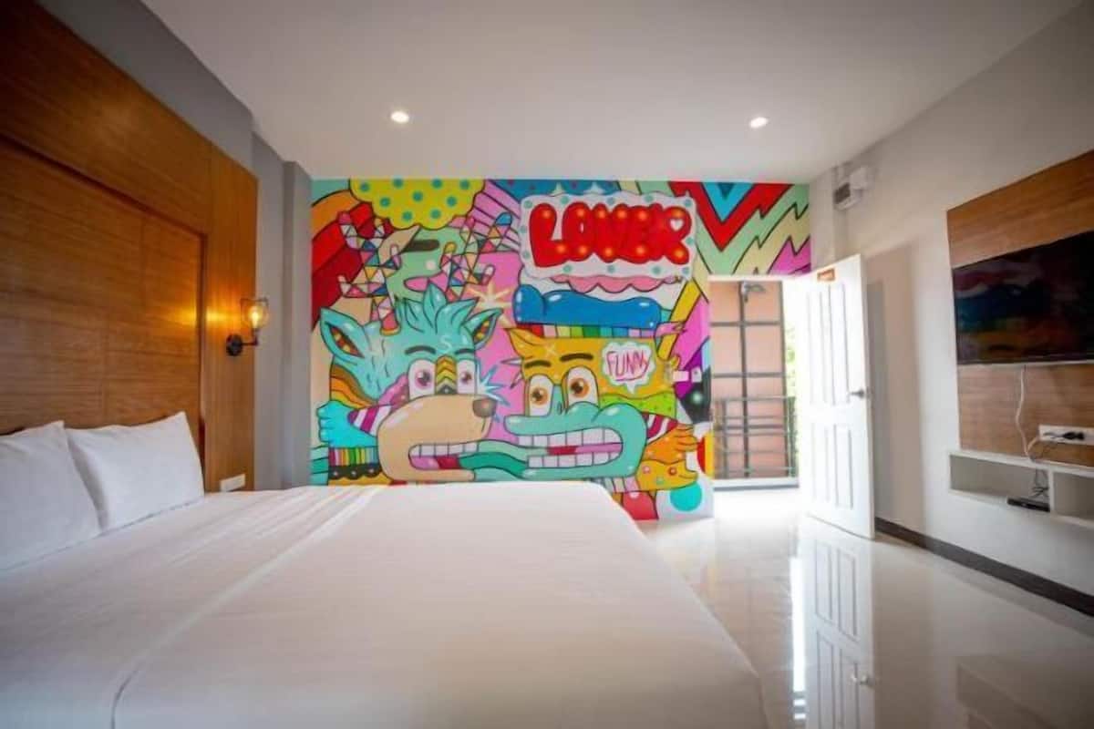 Una camera d'albergo con un letto grande, un murale colorato sulla parete e una testiera in legno.