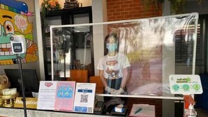 A reception desk with a glass partition, a digital device, and informational posters. - Smart Hotel (Lam Luk Ka)
