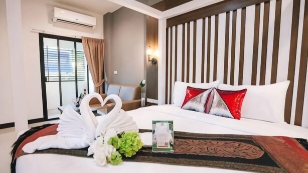 A hotel room with a bed, a window with curtains, a wall-mounted air conditioner, and a decorative wall panel. - Smart Hotel (Lam Luk Ka)