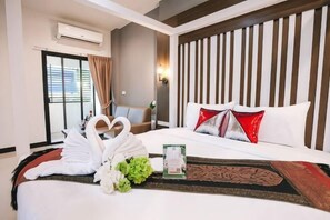 A hotel room with a bed, a window with curtains, a wall-mounted air conditioner, and a decorative wall panel. - Smart Hotel (Lam Luk Ka)