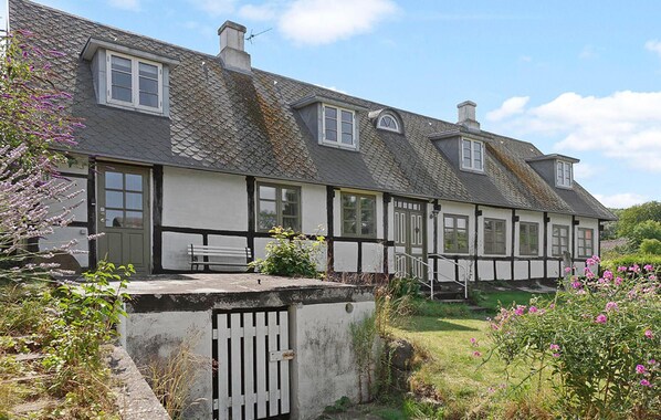 A traditional half-timbered house with a sloped roof, a front bench, and a gated entrance. - Lovely home in Samsø with WiFi (Samsø)
