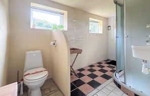 A bathroom with a toilet, a sink, and a shower. There are two windows and a towel rack. - Lovely home in Samsø with WiFi (Samsø)