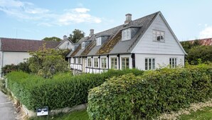 Een traditioneel huis met een puntige dakschild, witte gevel en meerdere ramen.