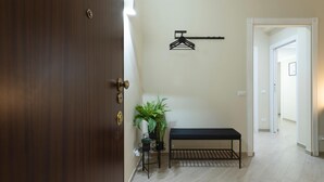 A hallway with a wooden door, a bench, a hanging light fixture, and a potted plant.