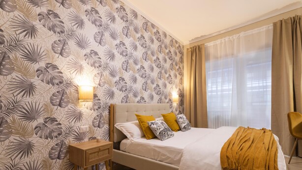 A bedroom with a bed, a nightstand, a lamp, and a window with curtains.