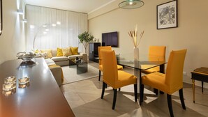 A modern living room with a sofa, coffee table, and dining area with yellow chairs.