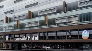 Ein modernes Hotelgebäude mit mehreren Etagen, großen Fenstern und einer auffälligen Beschilderung für "capsule hotel".