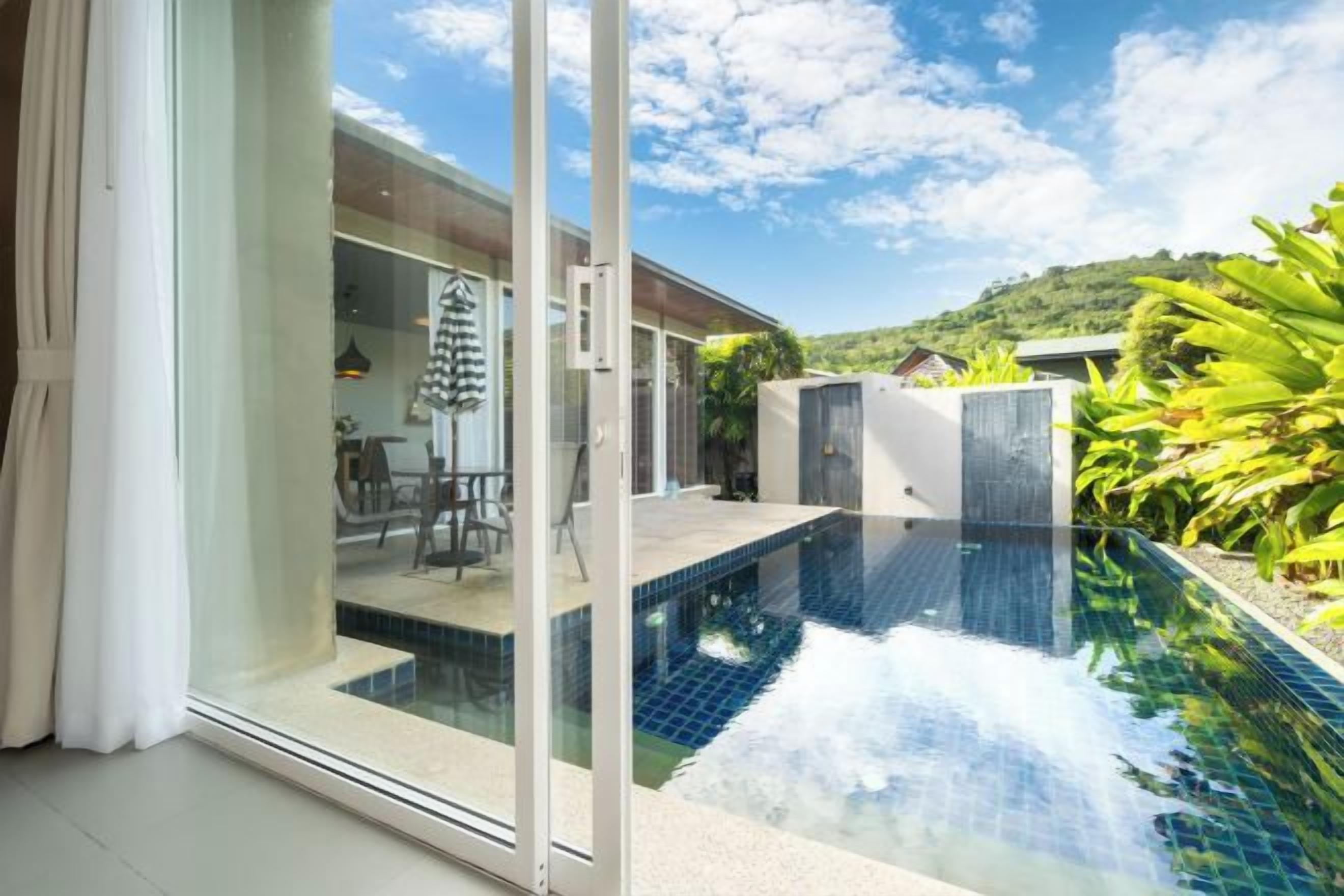 A modern house with a glass door leading to a swimming pool area.
