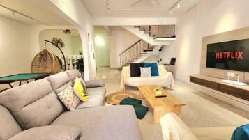A modern living room with a sofa, coffee table, and a TV displaying 'NETFLIX'.