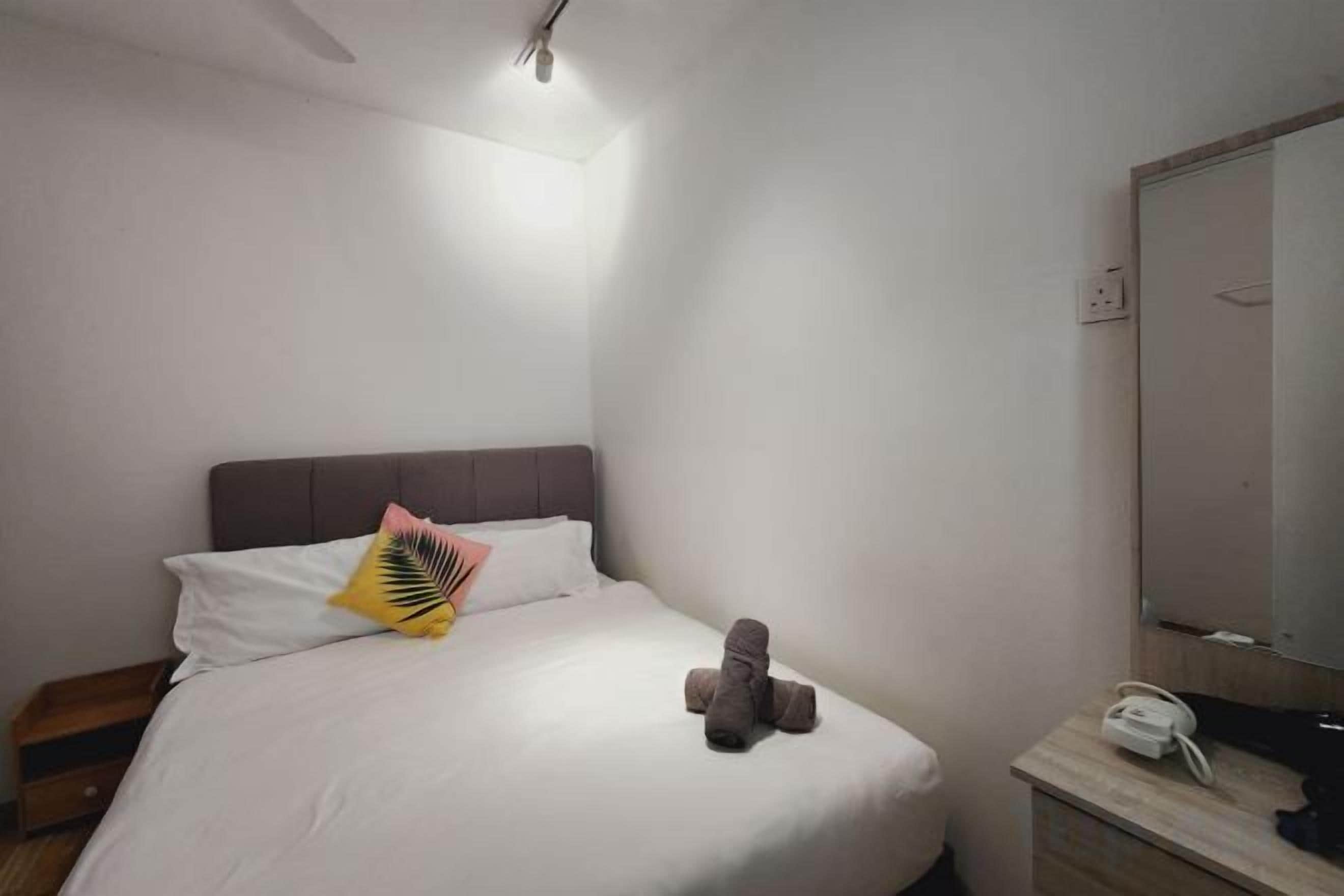 A hotel room with a bed, a bedside table with a phone, and a mirror.
