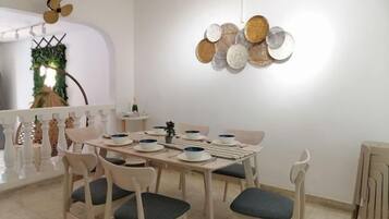 A dining area with a round table set for six, surrounded by six chairs with cushions.