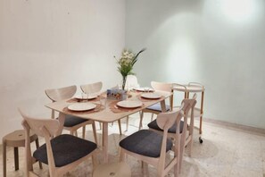 A dining area with a round table, six chairs, and a vase with flowers.