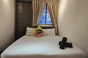 A neatly made bed with a pillow and a rolled towel, a window with curtains, and a wall with a patterned design. - Damansara Jaya Petaling Jaya 2 Storey Landed House for 15 Pax (Petaling Jaya)